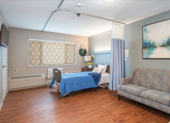 A well-organized hospital room featuring a bed, couch, and privacy curtains.