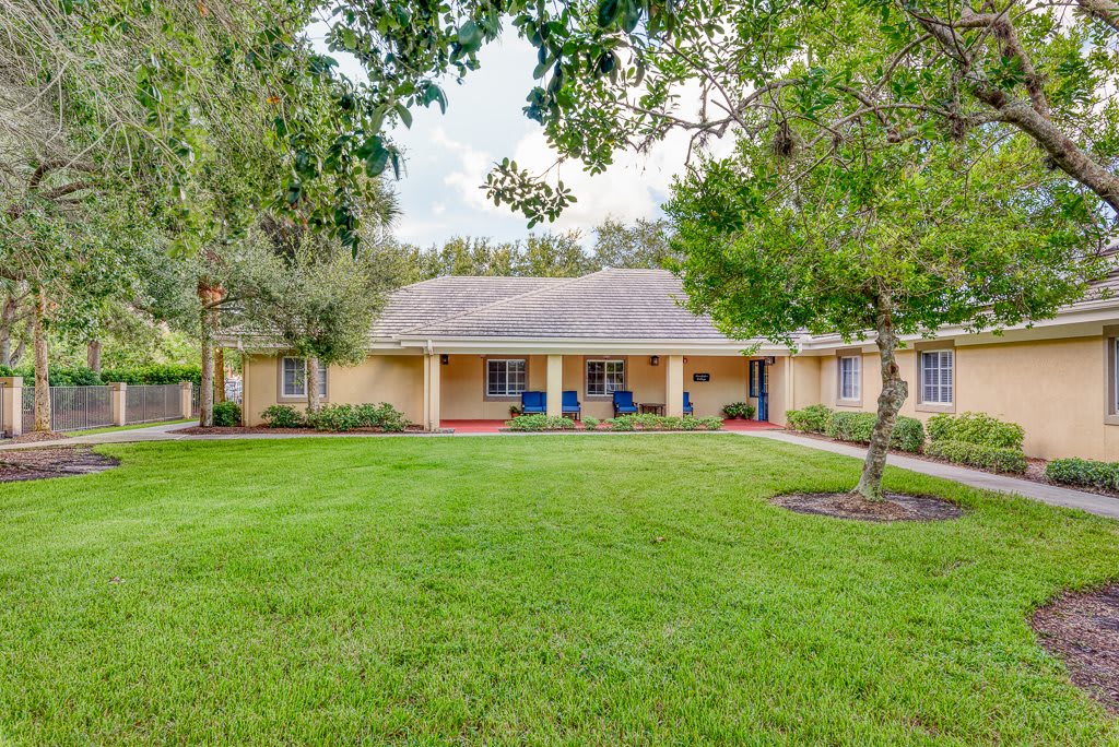 A suburban house with a well-maintained lawn and surrounding trees.