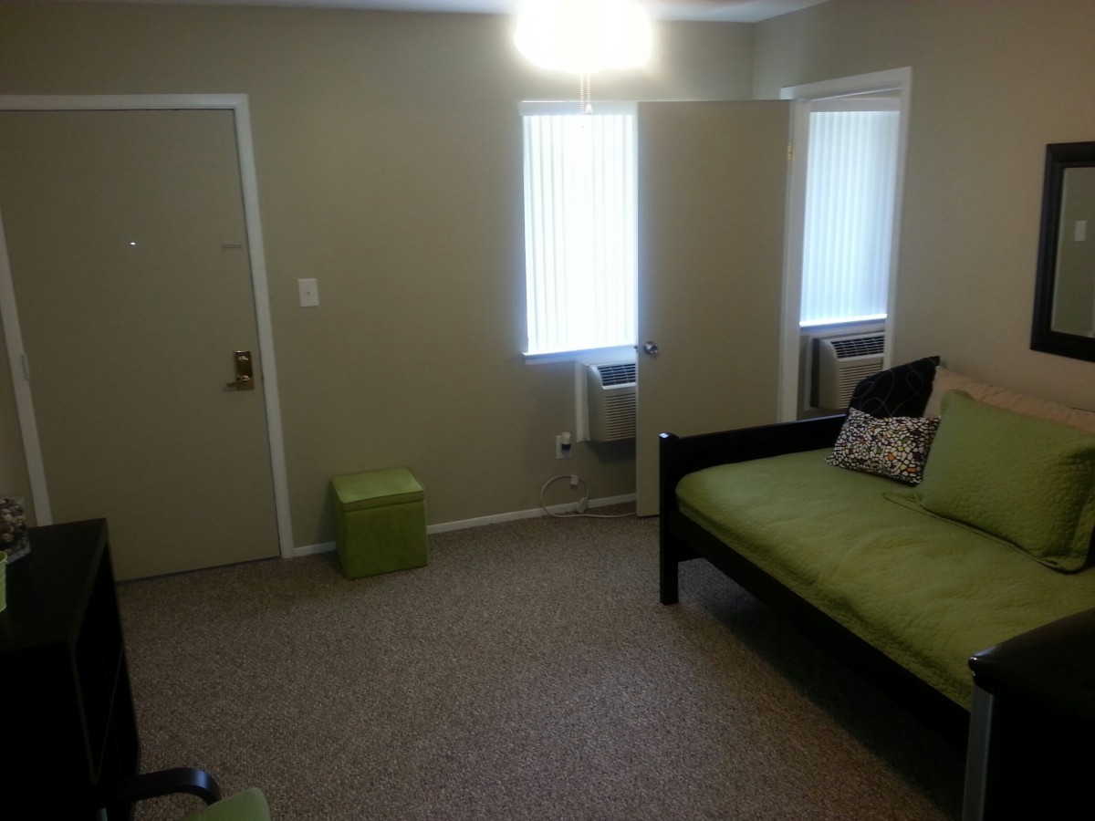 A simple, minimalist room with a bed and two windows.