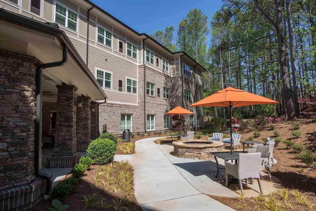 A modern apartment complex with outdoor seating and vibrant patio umbrellas along a landscaped pathway.