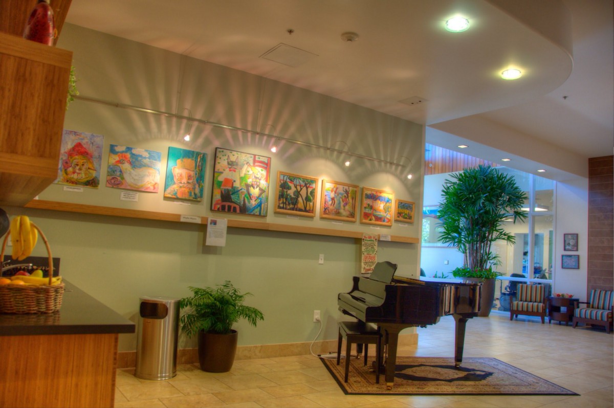 A modern indoor space featuring a piano and an art gallery display.