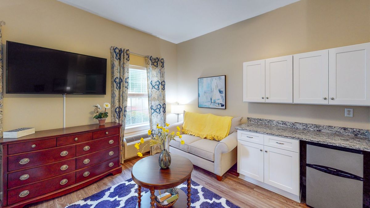 Cozy living room with a sofa, coffee table, and TV, adorned with decorative elements and bright window curtains.
