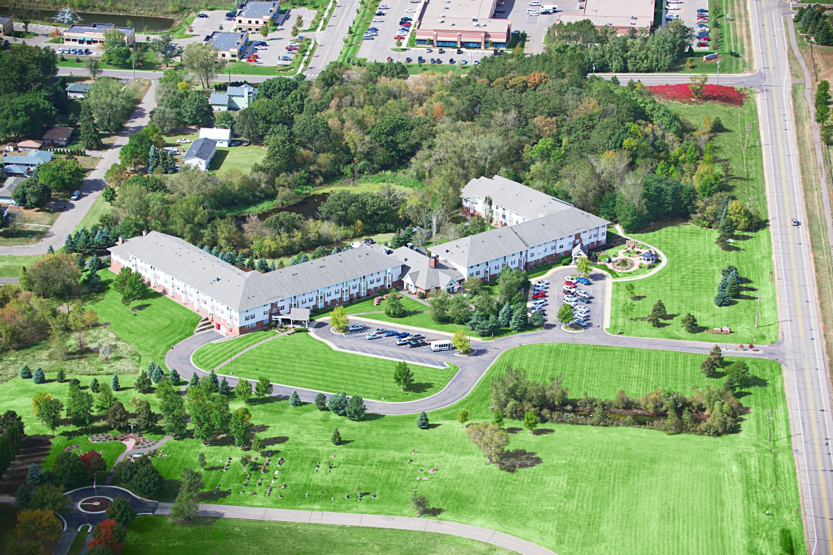 Aerial view of a large building complex surrounded by green landscapes and trees.