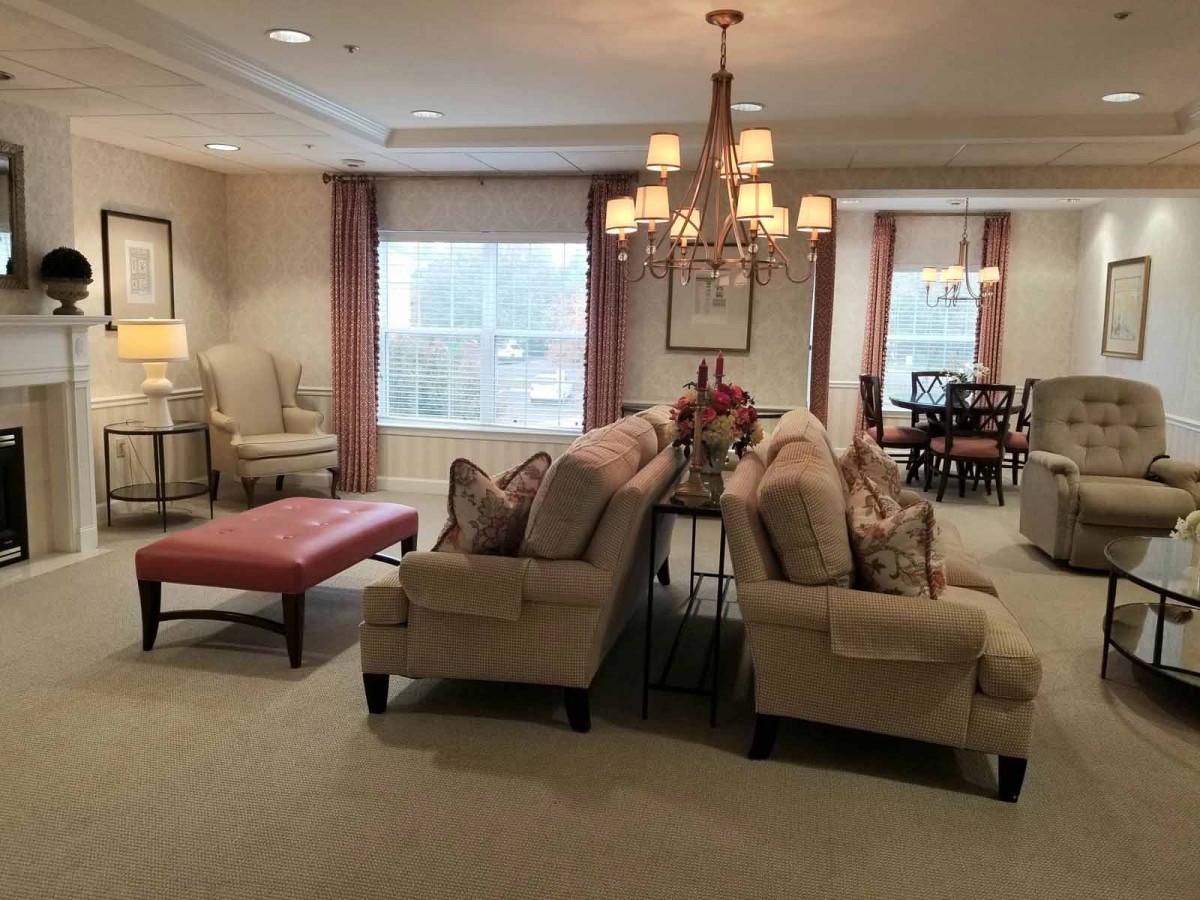 A cozy living room featuring elegant sofas, a chandelier, and large windows.