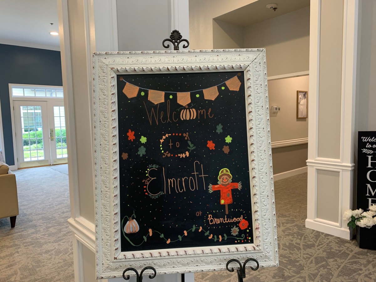 A welcoming chalkboard sign with autumn-themed decorations.