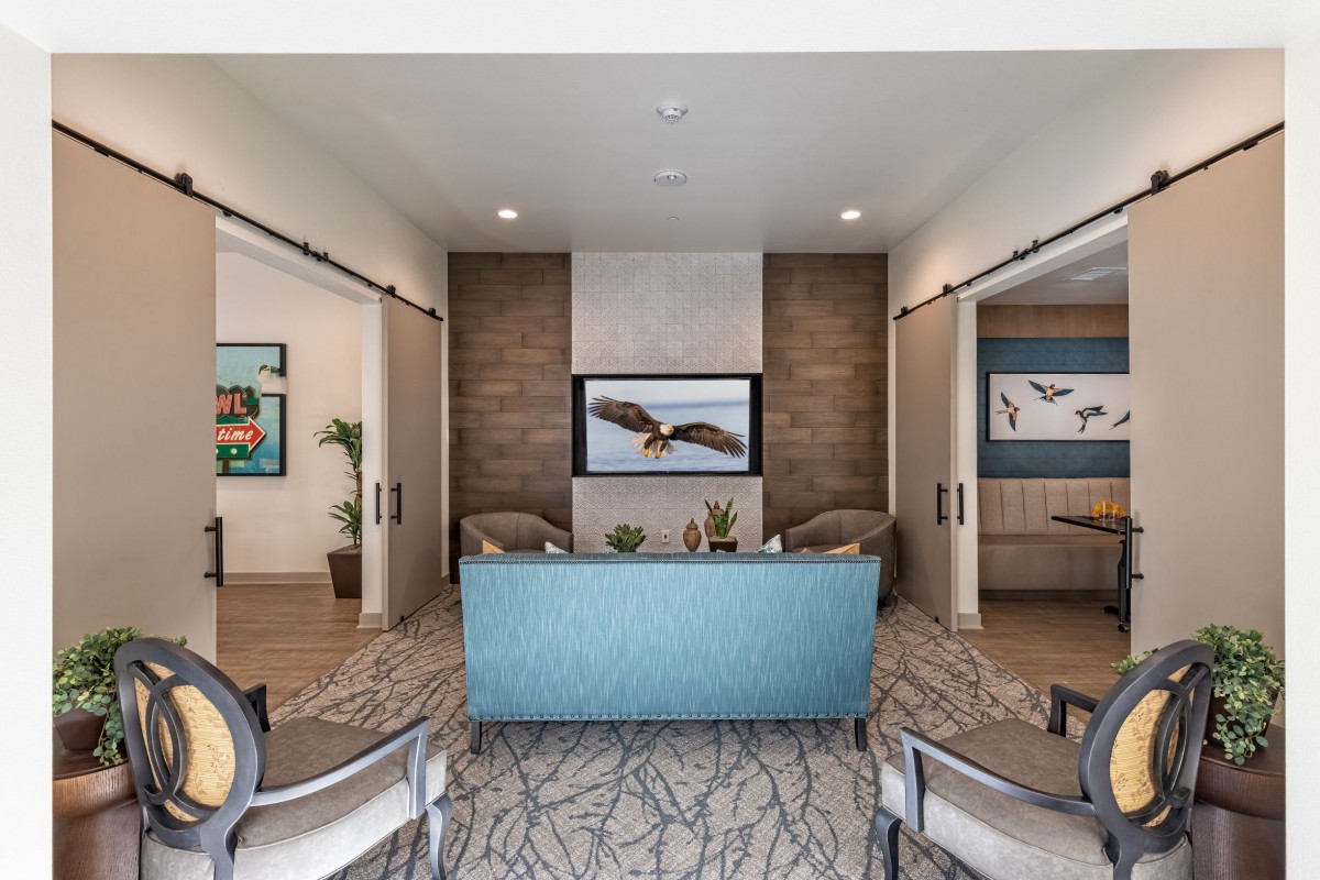 A modern living room with a blue sofa, television, and artwork on the walls.