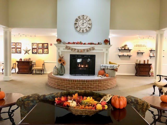 A cozy living room decorated for autumn, featuring a fireplace adorned with pumpkins and fall-themed ornaments.