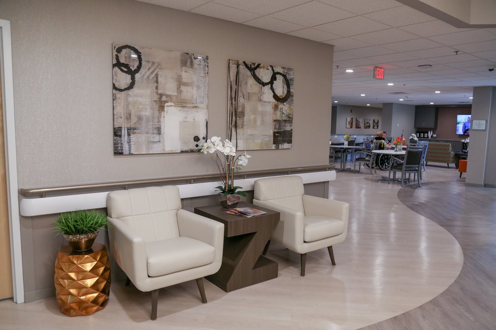 A modern lobby area featuring two chairs, a side table, and abstract artwork on the wall.