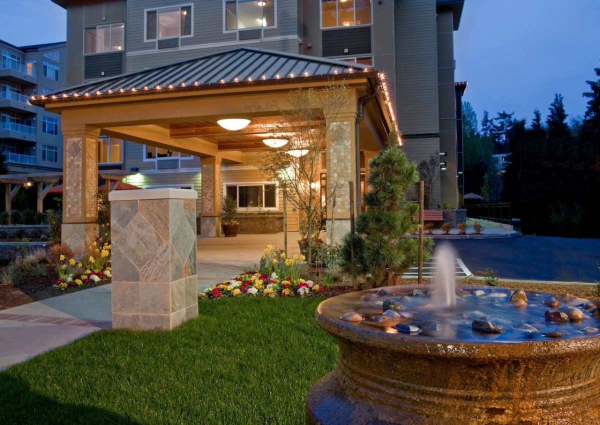 A hotel entrance featuring a decorative fountain and landscaped area at night.