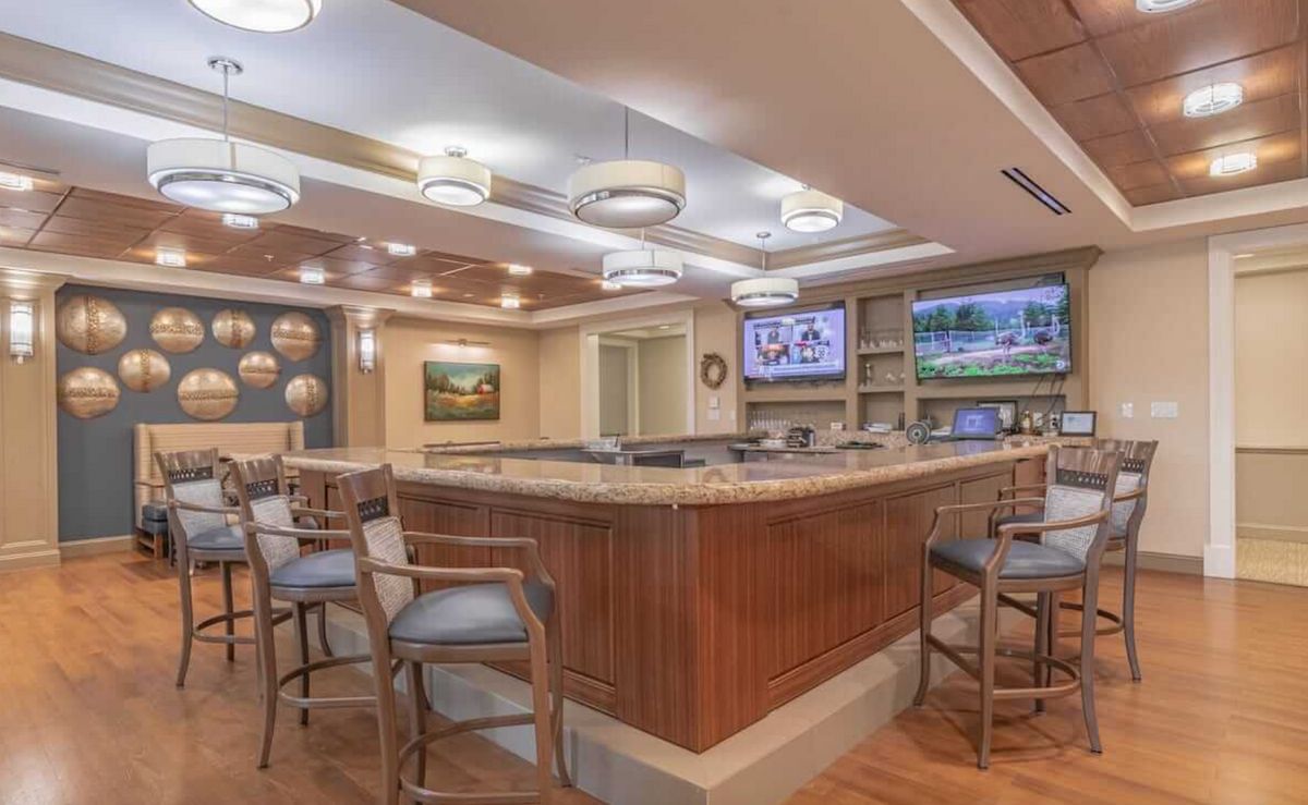 A modern bar interior with wooden decor, seating, and televisions.