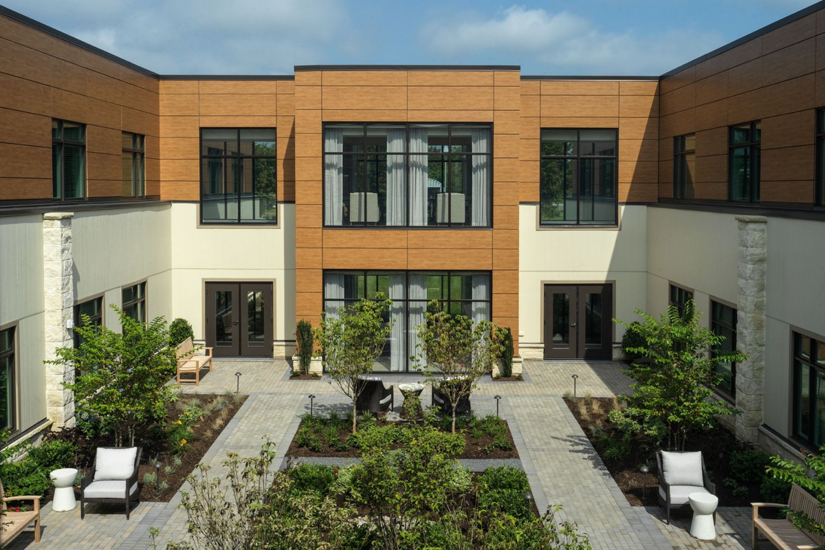 A modern two-story building with large windows and a landscaped courtyard.