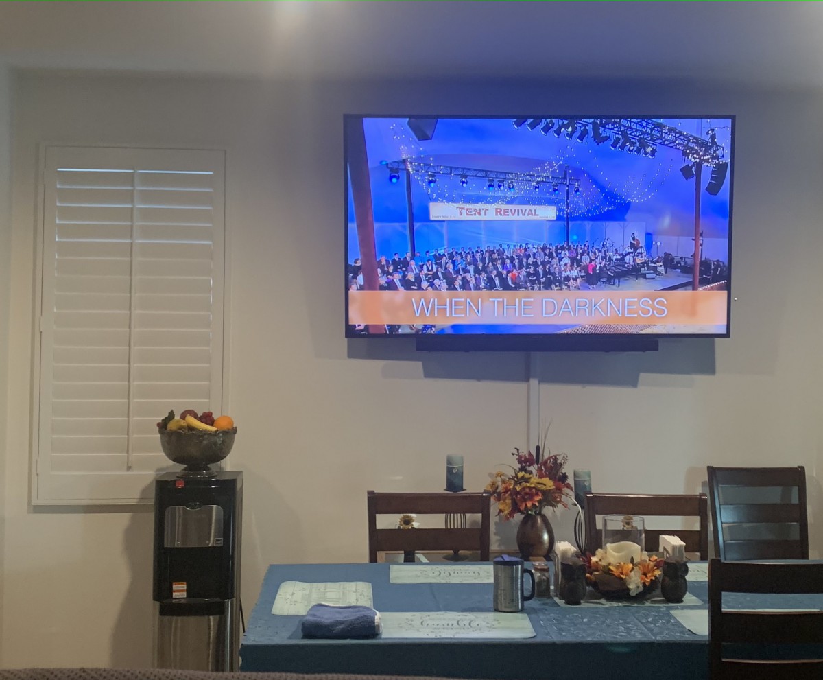 A modern living space with a wall-mounted TV above a dining area.