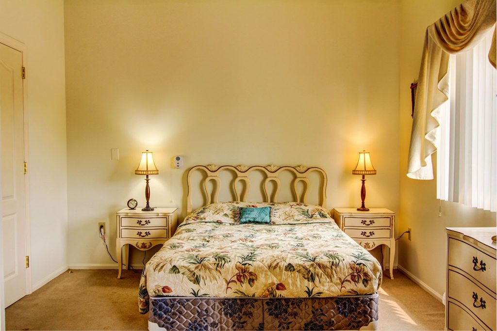 A vintage-style bedroom with a patterned bedspread, two lamps, and nightstands.