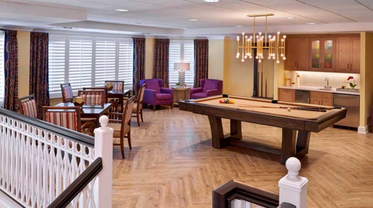 A cozy game room featuring a pool table, comfortable seating, and elegant lighting.