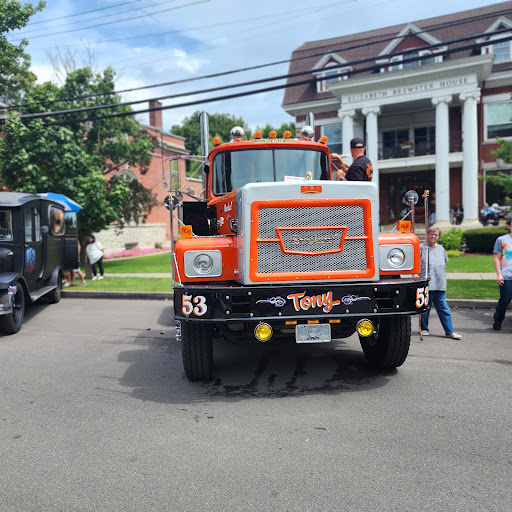 A vibrant orange truck parked on the street, surrounded by people and buildings.