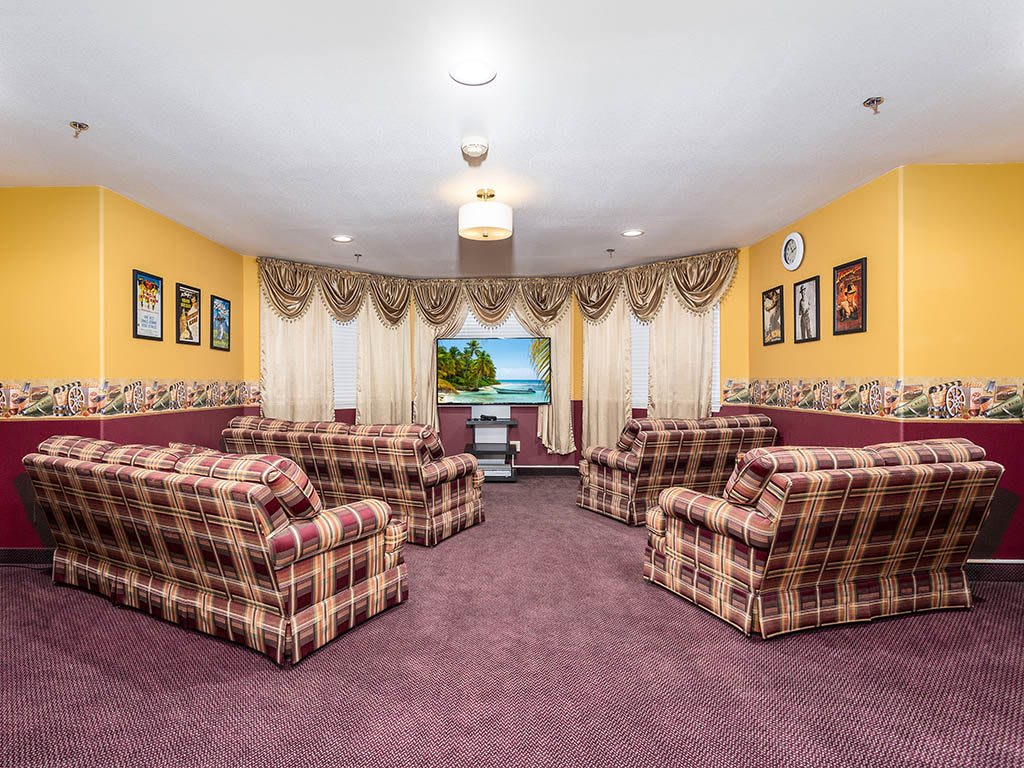 A cozy living room with plaid sofas, a television, and decorative curtains.