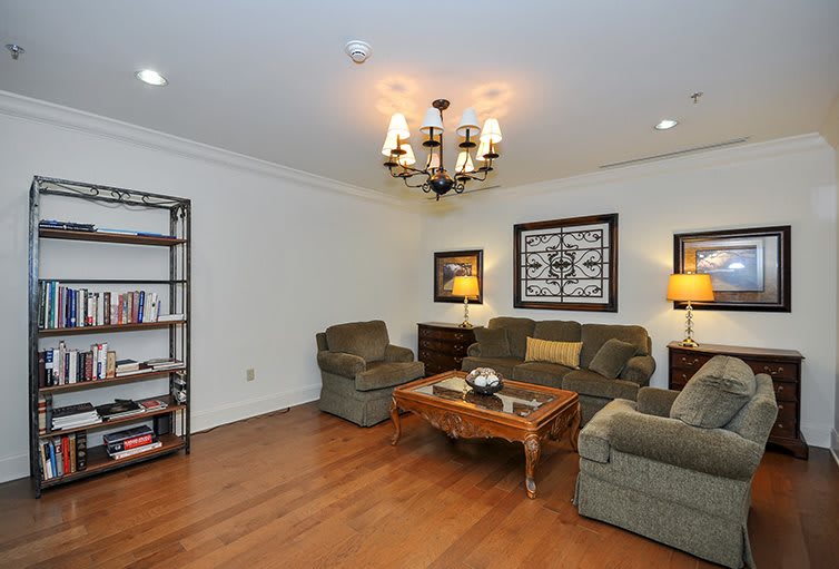 A cozy living room with comfortable seating, a wooden coffee table, elegant lighting, and decorative artwork.