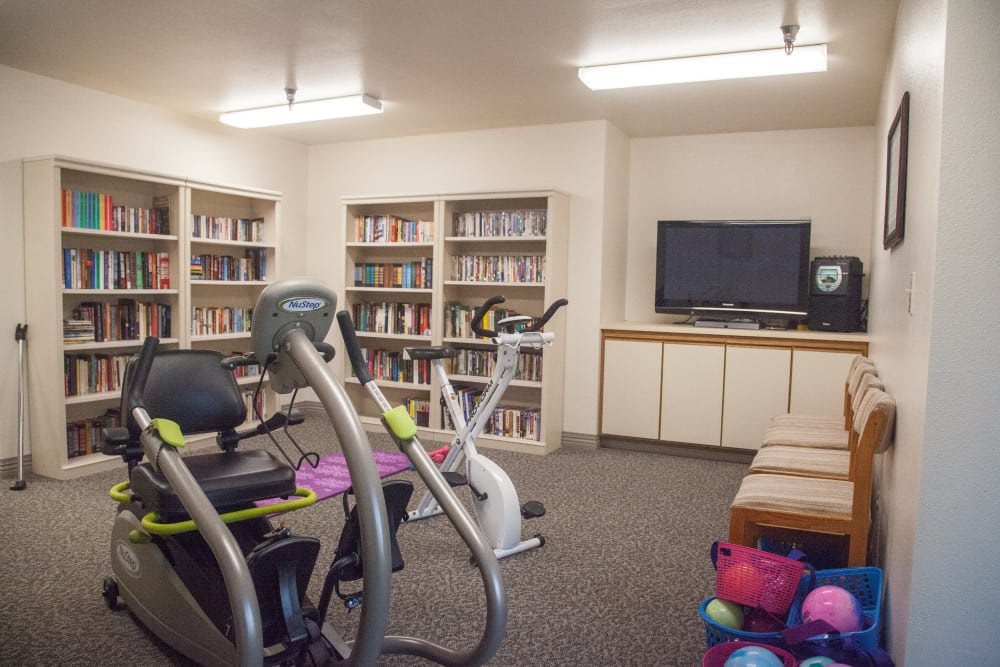 A multi-use room combining a gym and library, featuring exercise equipment and bookshelves.