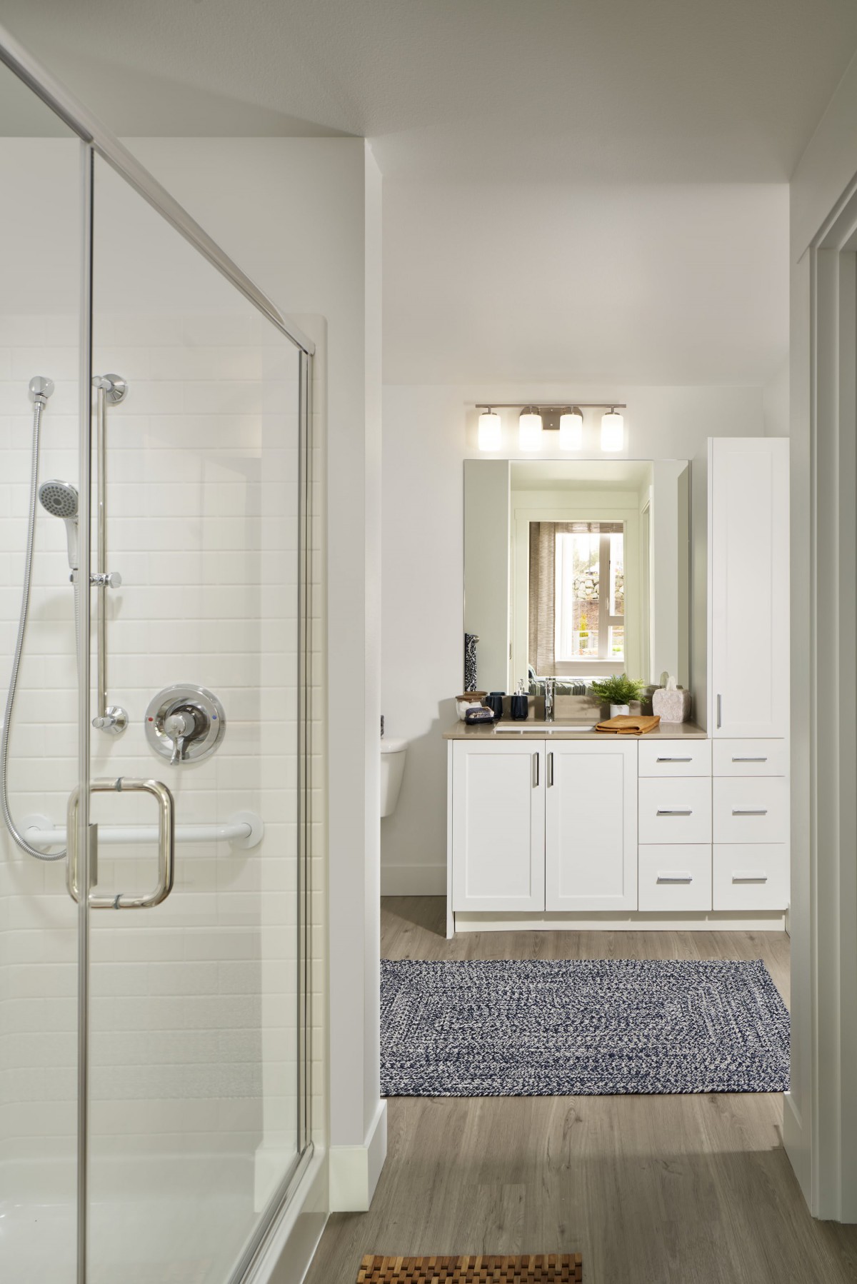 A modern, well-lit bathroom featuring a glass shower and a white vanity with decorative elements.