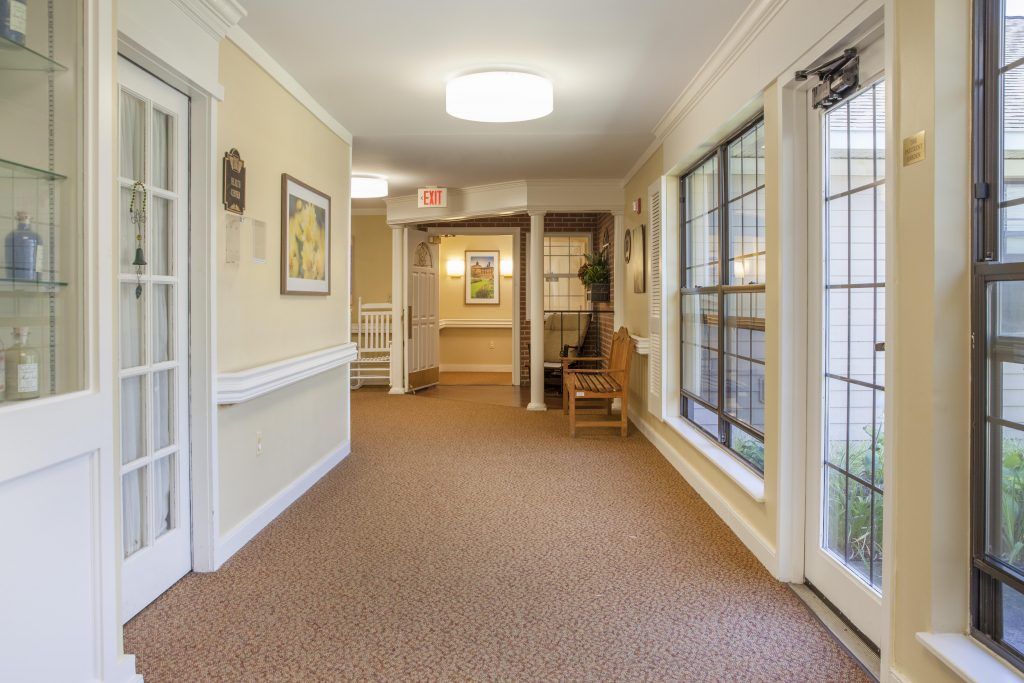 A well-lit hallway with large windows and carpeted flooring.