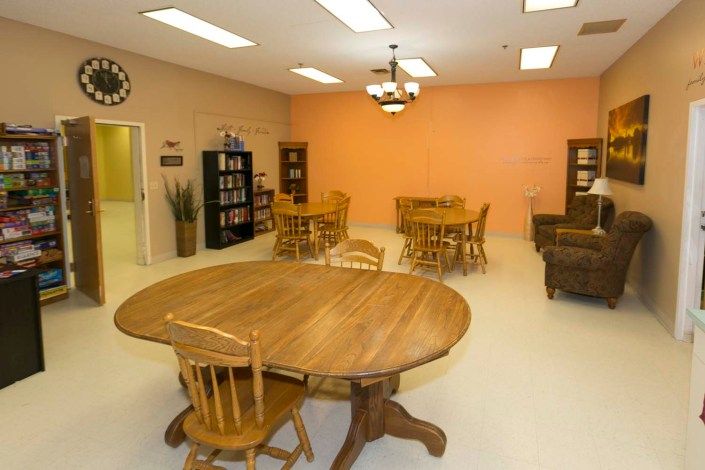A cozy room with wooden tables and chairs, bookshelves, and warm lighting.