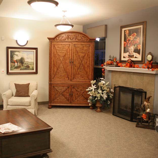 A cozy living room with a fireplace, armchair, and elegant wooden wardrobe.