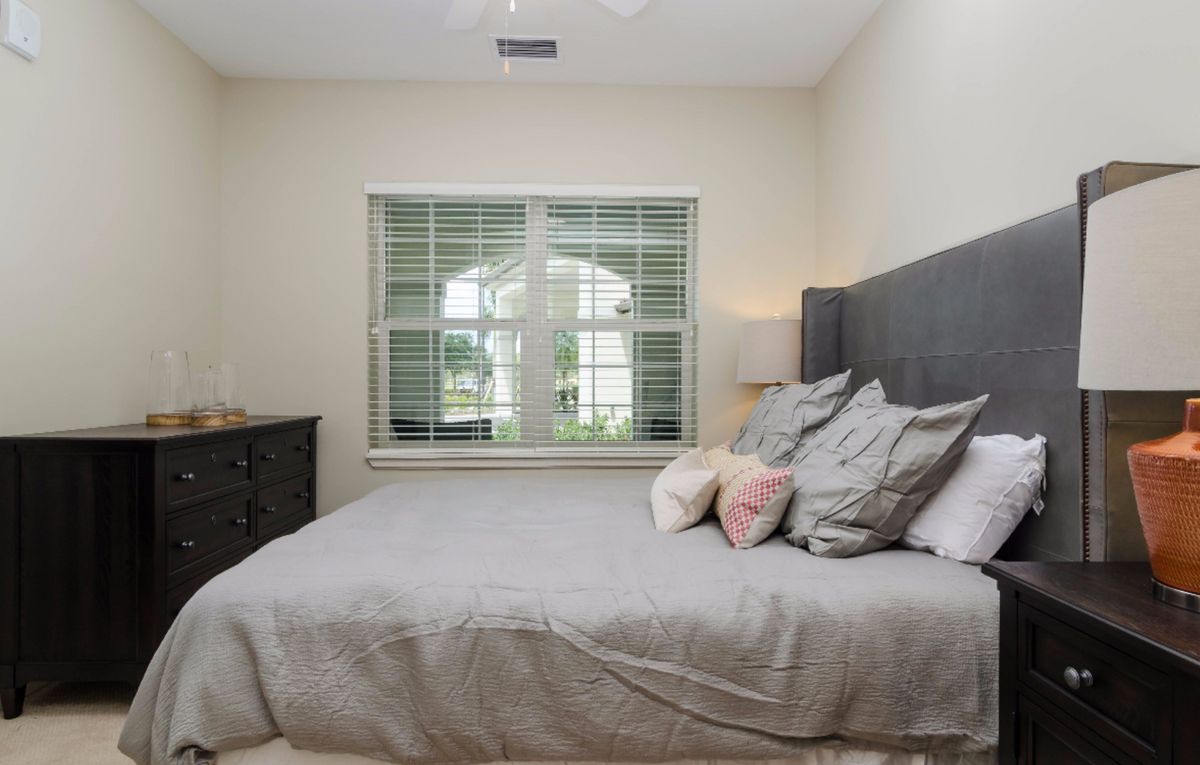 A cozy bedroom with a neatly made bed and a window letting in natural light.