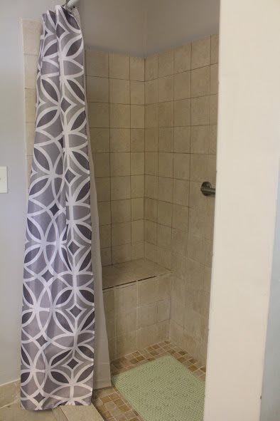 A tiled shower with a patterned curtain.