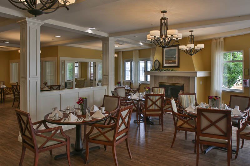 A cozy dining room with elegant chandeliers and neatly arranged tables and chairs.