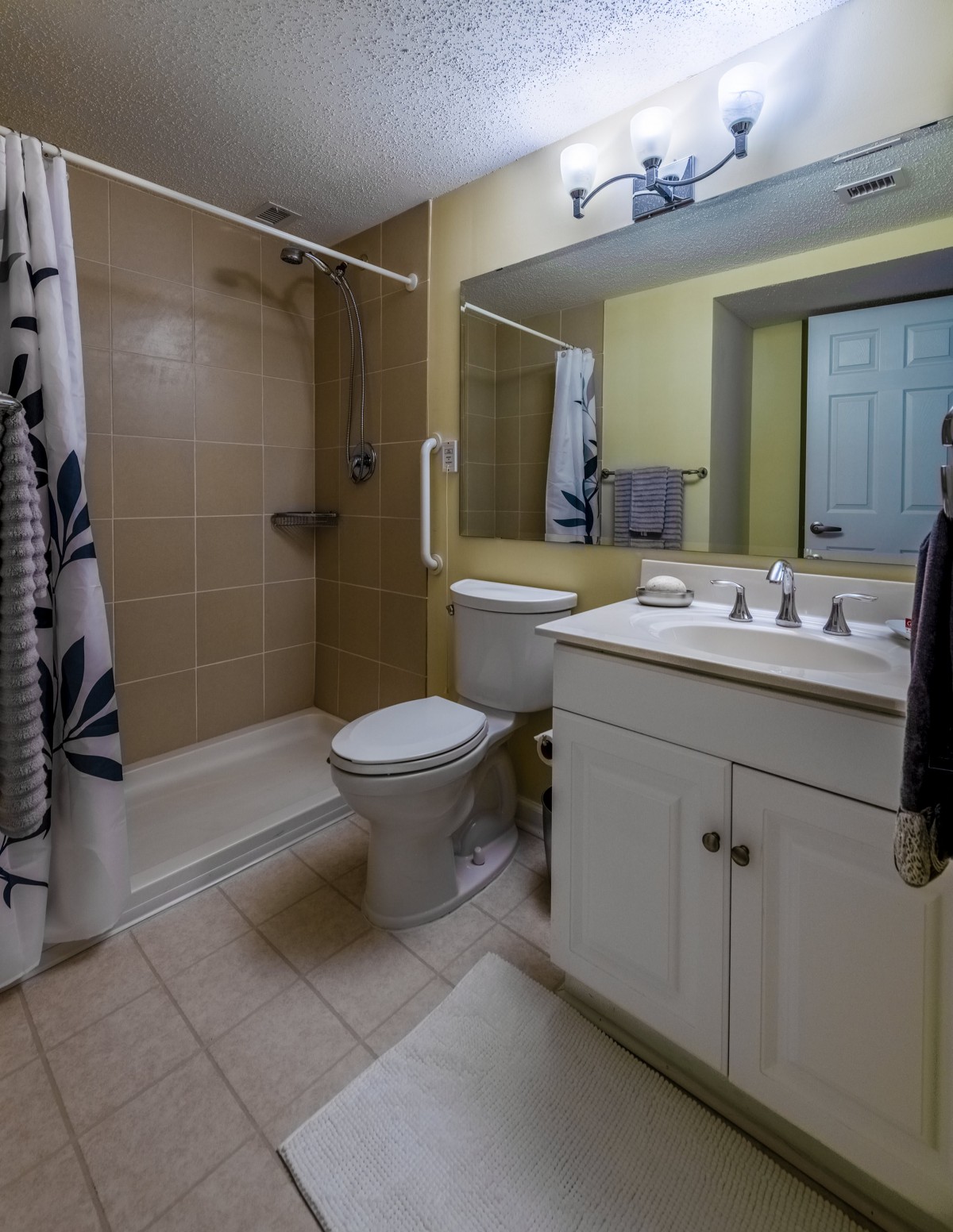 A modern bathroom featuring a shower, toilet, sink, and mirror.