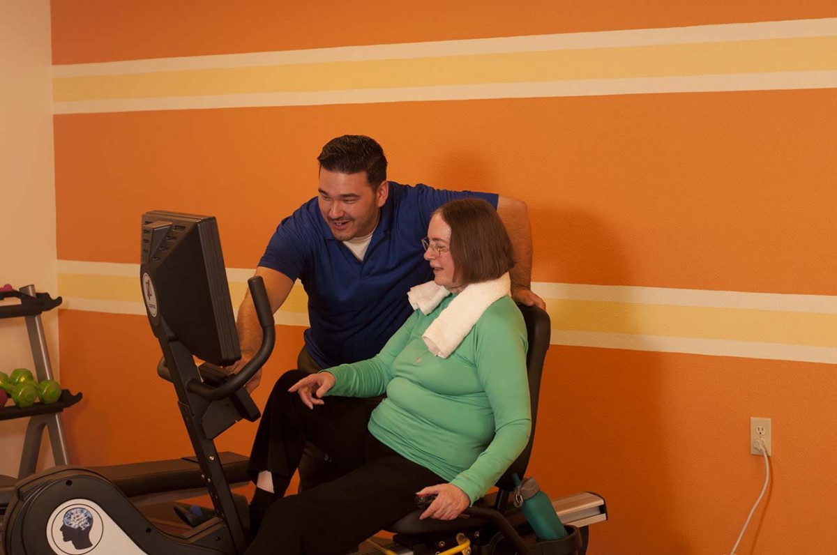 A senior woman receives guidance from a therapist during her exercise session.