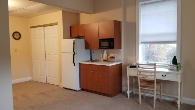 A compact kitchen area in an apartment with a refrigerator, microwave, and cabinets.