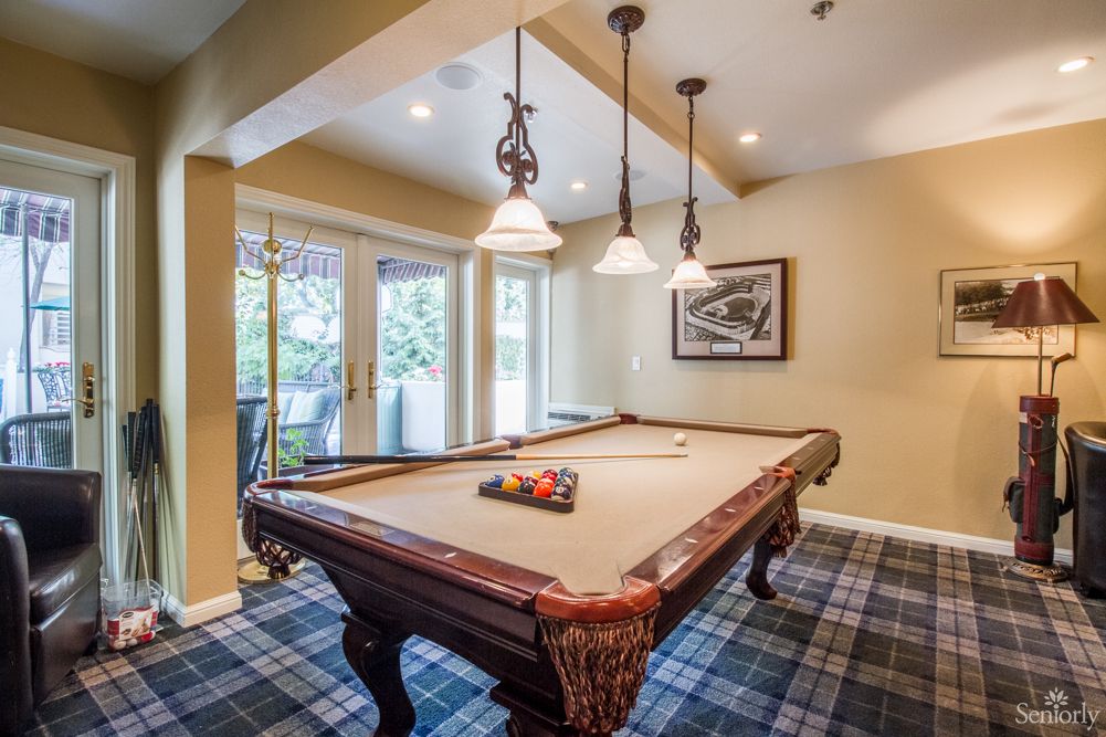 A cozy game room featuring a billiards table with pendant lighting and a view of the outdoors.