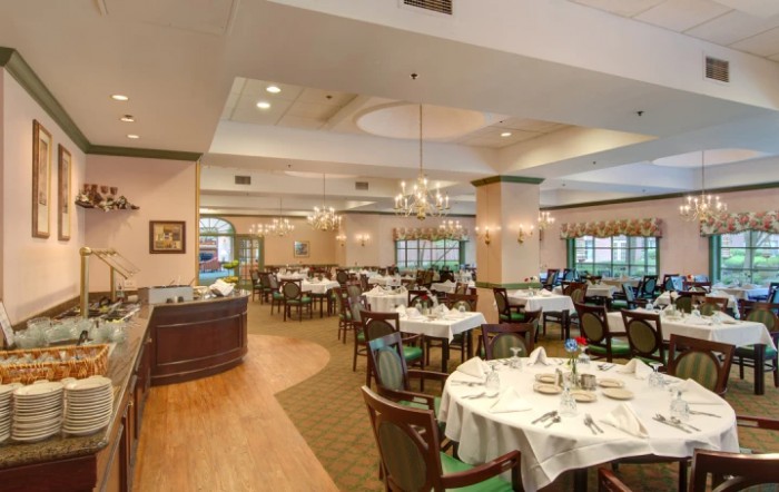 An elegant restaurant dining room with neatly arranged tables and chandeliers.