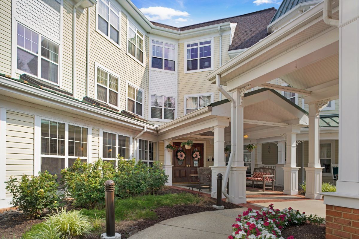 The entrance to a residential building with a covered porch and landscaped surroundings.