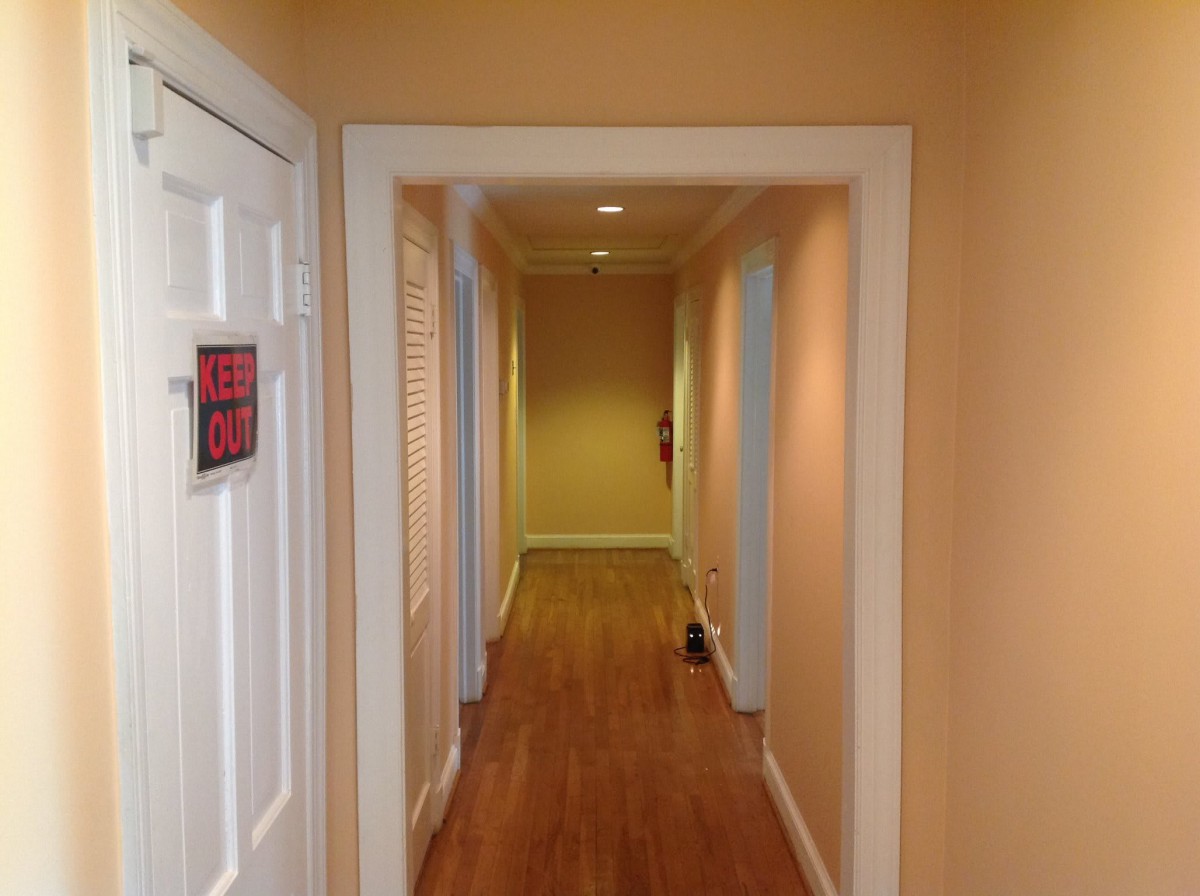 A hallway with wooden flooring and doors on either side.
