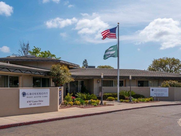 An office building with an American flag and a secondary flag flying at the entrance.