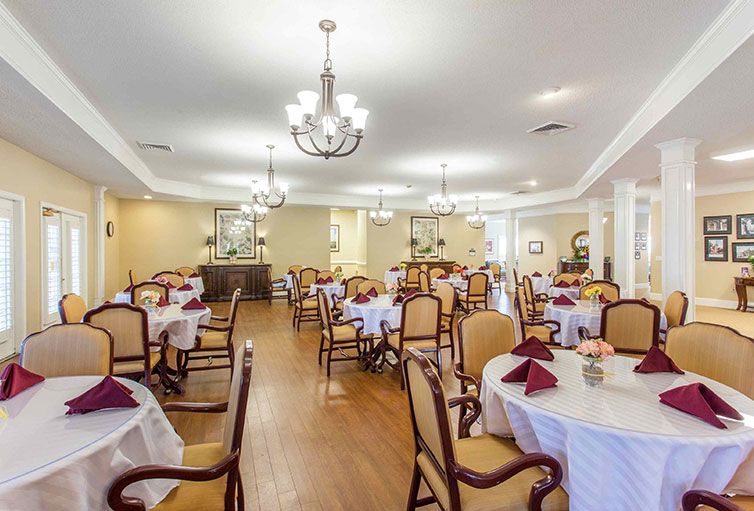 A spacious and elegant dining room with neatly arranged tables and chairs, adorned with chandeliers.