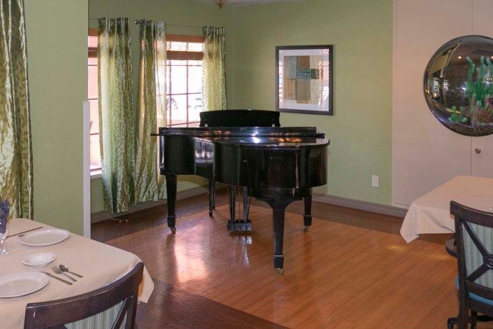 A grand piano in a cozy living room with green walls and hardwood flooring.