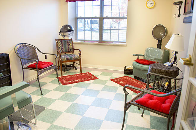 A cozy hair salon with vintage-style chairs and a checkered floor.