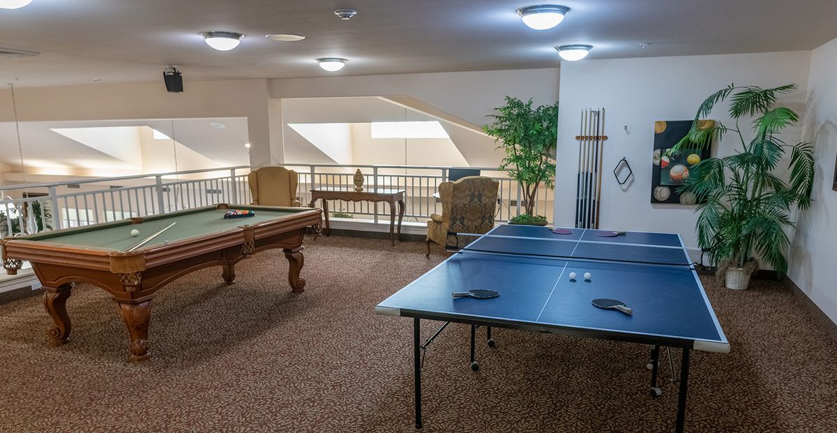 A cozy game room featuring a pool table and a ping pong table with comfortable seating.