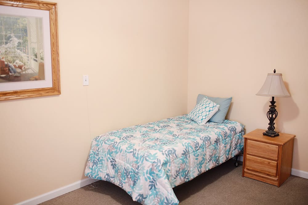 A simple bedroom with a single bed and nightstand.