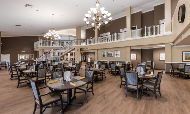 A spacious and elegantly designed dining area with modern furnishings and chandeliers.