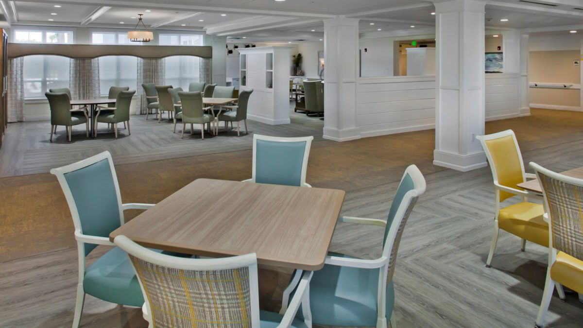 A modern dining area with wooden tables and cushioned chairs.