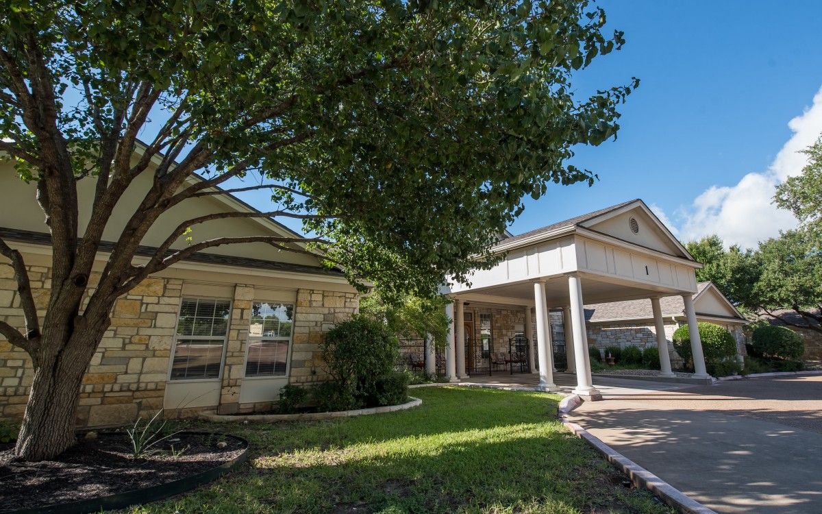 A suburban house with a spacious front yard and a large tree.