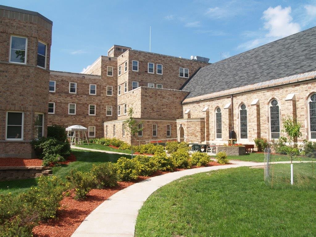 A serene college campus with brick buildings and a landscaped pathway.