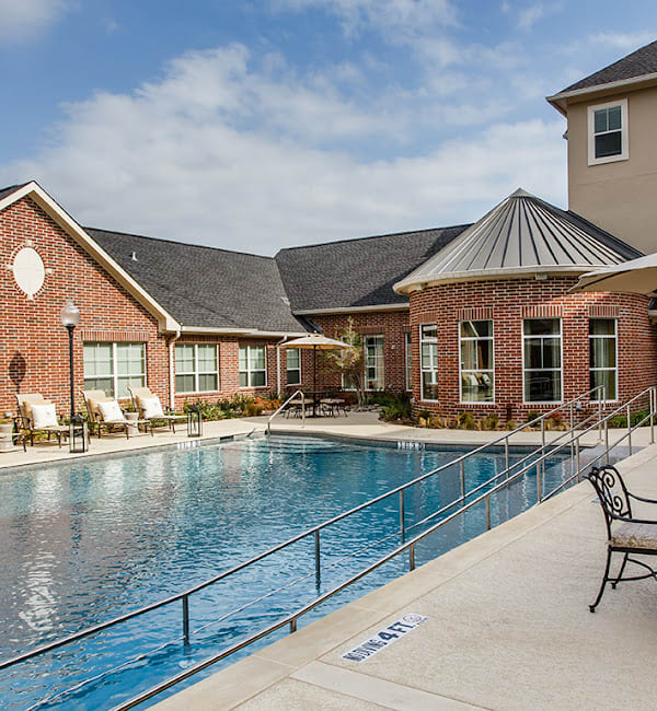 A residential complex with a swimming pool and brick buildings under a clear sky.