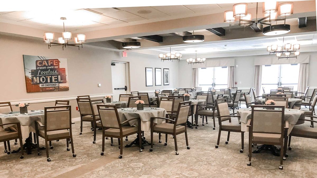 An elegant banquet room with neatly arranged tables and chairs, featuring soft lighting and large windows.