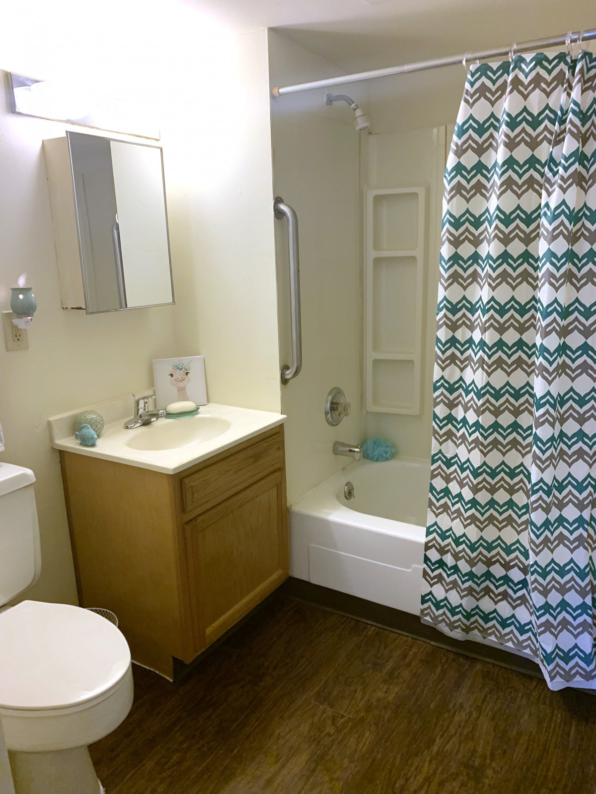A modern bathroom featuring a sink, bathtub with a patterned shower curtain, and a toilet.