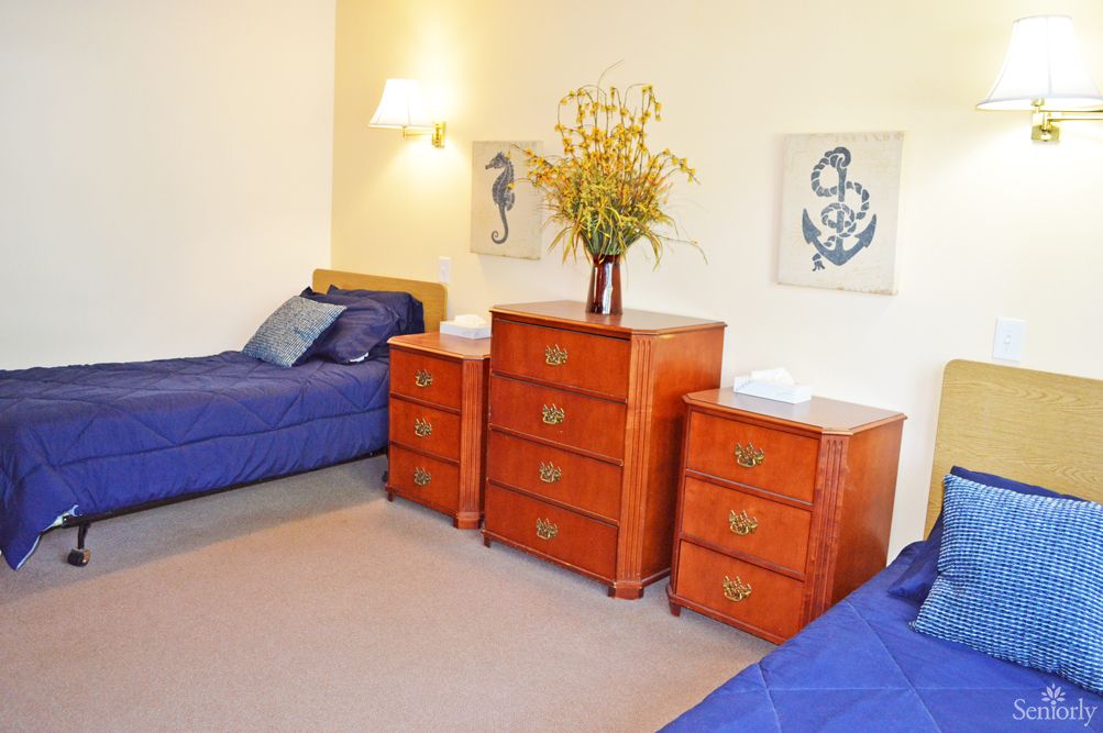 A cozy bedroom with twin beds, featuring a nautical-themed decor and wooden furniture.